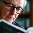 Un uomo con gli occhiali che legge un libro, simboleggiando una libreria di contenuti curati da esperti.